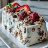 Creamy frozen yogurt bark topped with vibrant berries and crunchy granola, perfect for snacking.