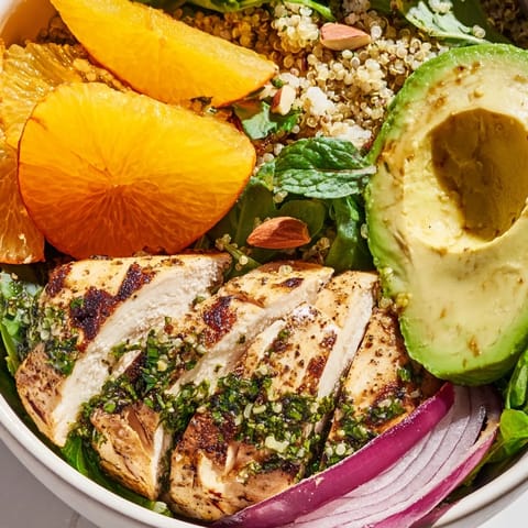 Freshly grilled herb-marinated chicken slices rest atop a vibrant bowl of quinoa, mixed greens, and juicy orange segments in this hearty Citrus Herb Chicken Salad Bowl.