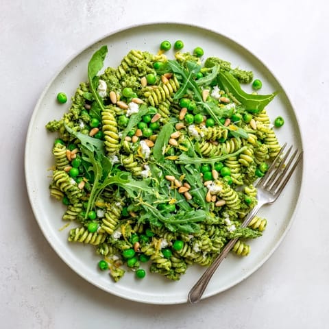 Fresh Spring Green Pesto Pasta Salad tossed with basil pesto, bright peas, and lemon zest, ready for a spring lunch.  