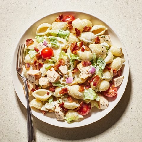 Tossed in a light creamy mayo dressing, BLT Chicken Pasta Salad is garnished with fresh herbs and pepper for a flavorful potluck main dish.  