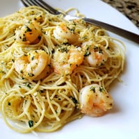 Freshly cooked angel hair pasta tossed in a zesty lemon-garlic butter sauce with succulent shrimp, garnished with parsley and lemon wedges for a bright, weeknight dinner.