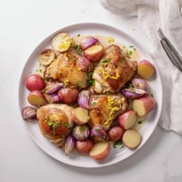 Golden roasted radish and chicken thighs on a sheet pan, garnished with fresh parsley and lemon zest for a bright finish.
