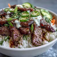 A vibrant Korean Beef Power Bowl with sesame-ginger beef, fluffy rice, tangy pickled carrots, and creamy sriracha mayo.