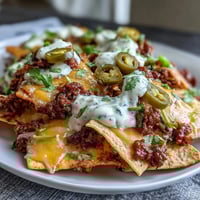 A generous platter of loaded baseball nachos with jalapeños and cheese sauce, ready for game day enjoyment.  