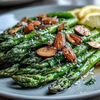 Bright asparagus spears sautéed in lemon butter, topped with golden toasted almonds for a fresh spring side dish.